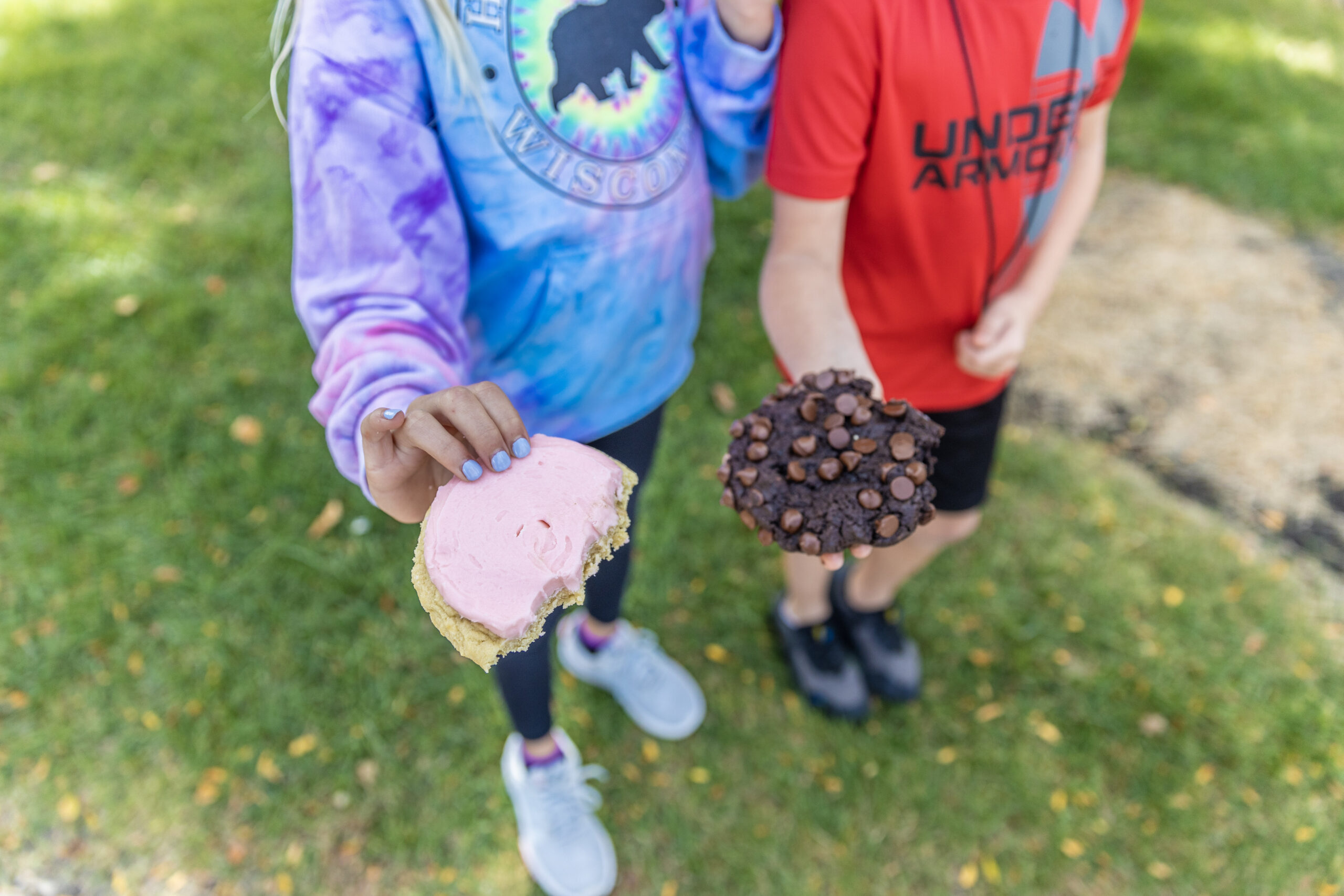 Two kids showcasing their treats from Crumbl Cookies.