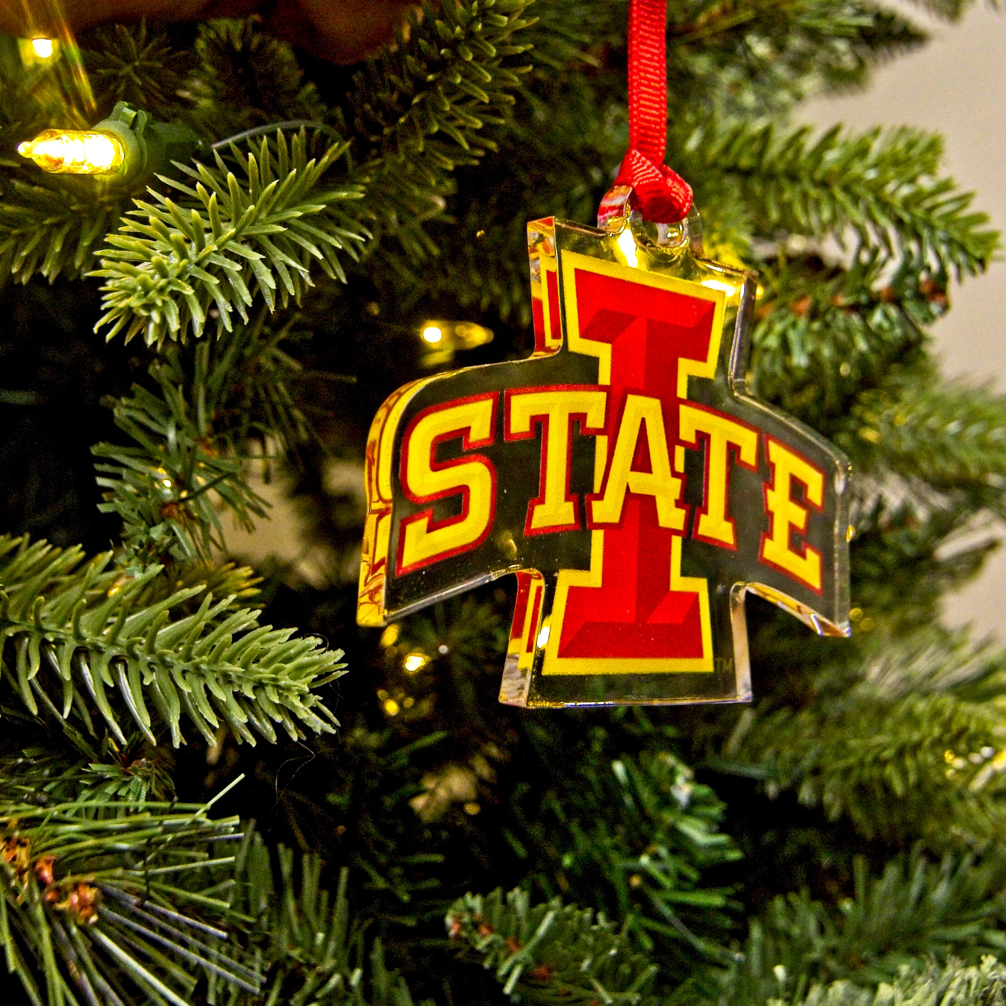 Iowa State Cyclone logo ornament hanging off of a Christmas tree.