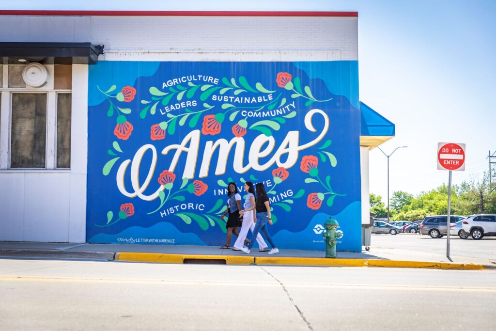 A group of girls walking past a mural in Ames, Iowa.