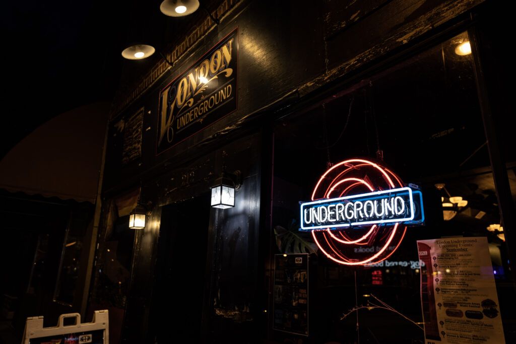 Dark image of outside a British pub. LED sign that says "London Underground".