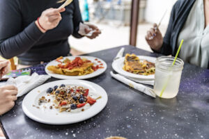 A Coffee Lovers' Perfect Weekend in Ames - Lockwood CafeWomen eating at a picnic table outside of Lockwood Cafe with crepes and a drink, chatting.