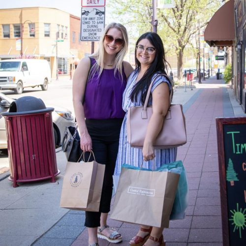 Two locals posing with their new bags after shopping in downtown Ames.